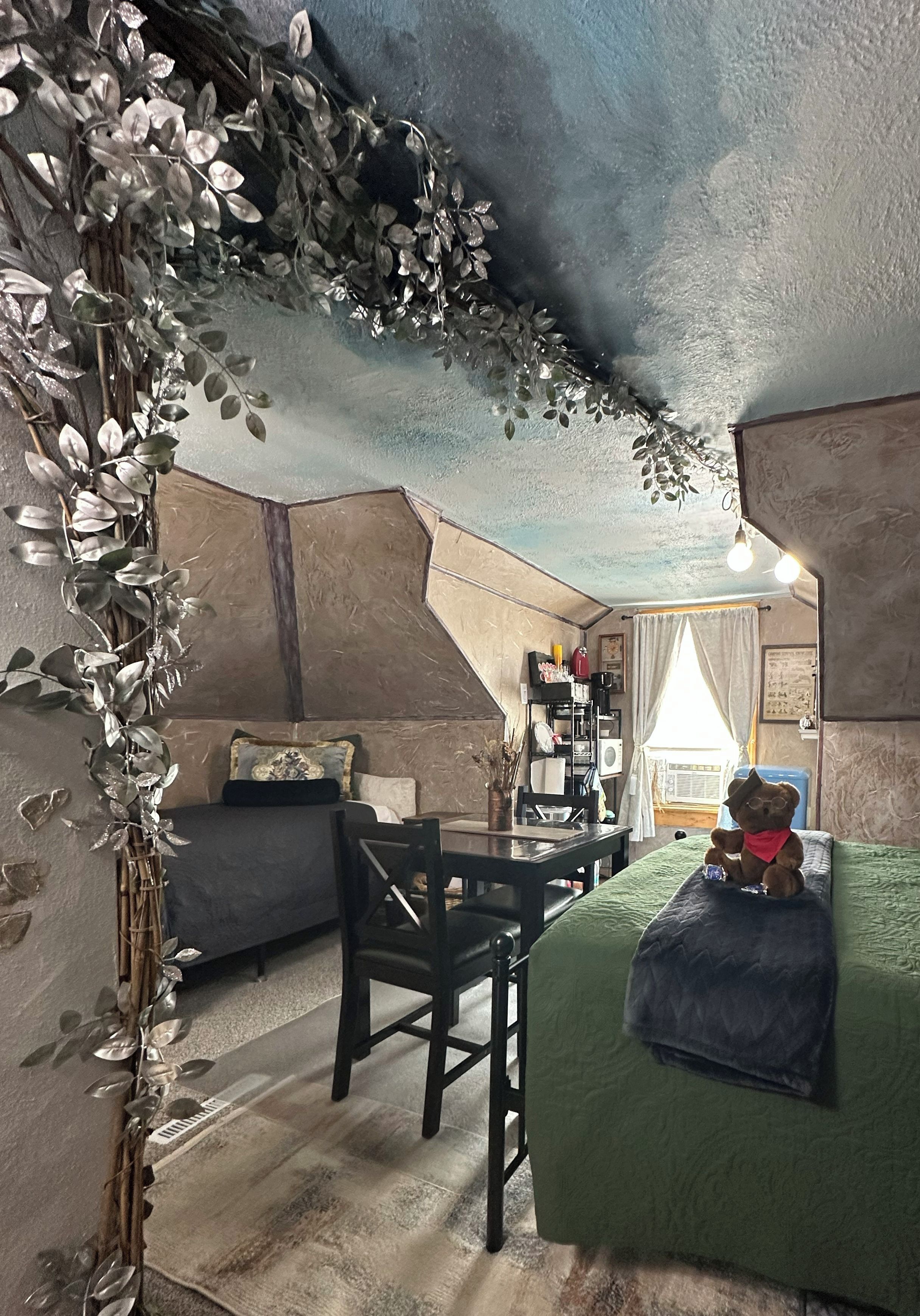 A cozy room with a bed, a chair, a desk, and a teddy bear.