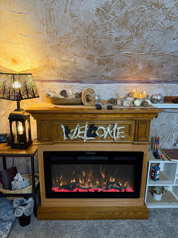 A fireplace with a 'WELCOME' sign, a lamp, and decorative items on the mantel.