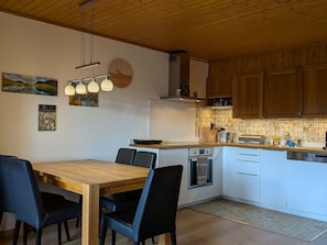 Eine Küche mit Holzausstattung, einer weißen Arbeitsplatte und einem Essbereich mit Holztisch und Stühlen.