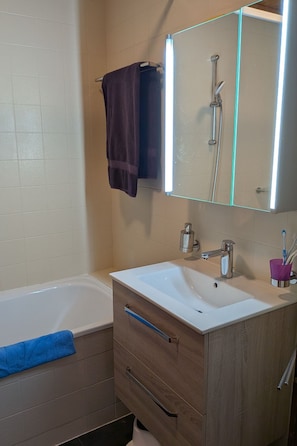Un bagno con una vasca, un lavabo, uno specchio e un portasciugamani.