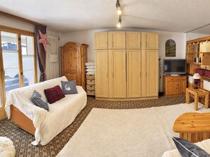A cozy living room with a sofa, a television, and a large wooden wardrobe. - Residenz Albina Leukerbad # 4-bed apartment, Dusche, WC by Interhome (Leukerbad)