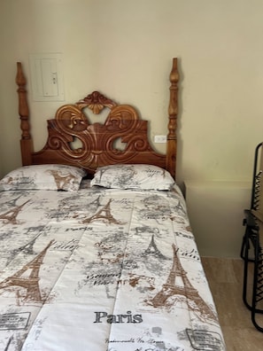 A bed with a Paris-themed bedspread, a wooden headboard, and a plain wall. - Beautiful 4-bedroom apartment with AC in Saint Ann's Bay (Saint Ann's Bay)