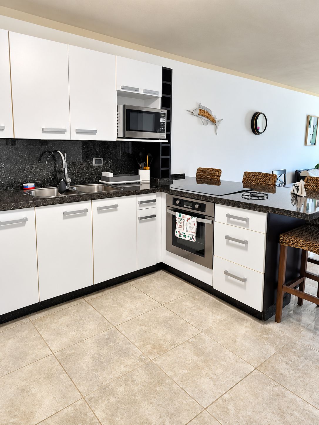 Een moderne keuken met witte kasten, een zwart aanrecht, een magnetron, een fornuis en een spoelbak.