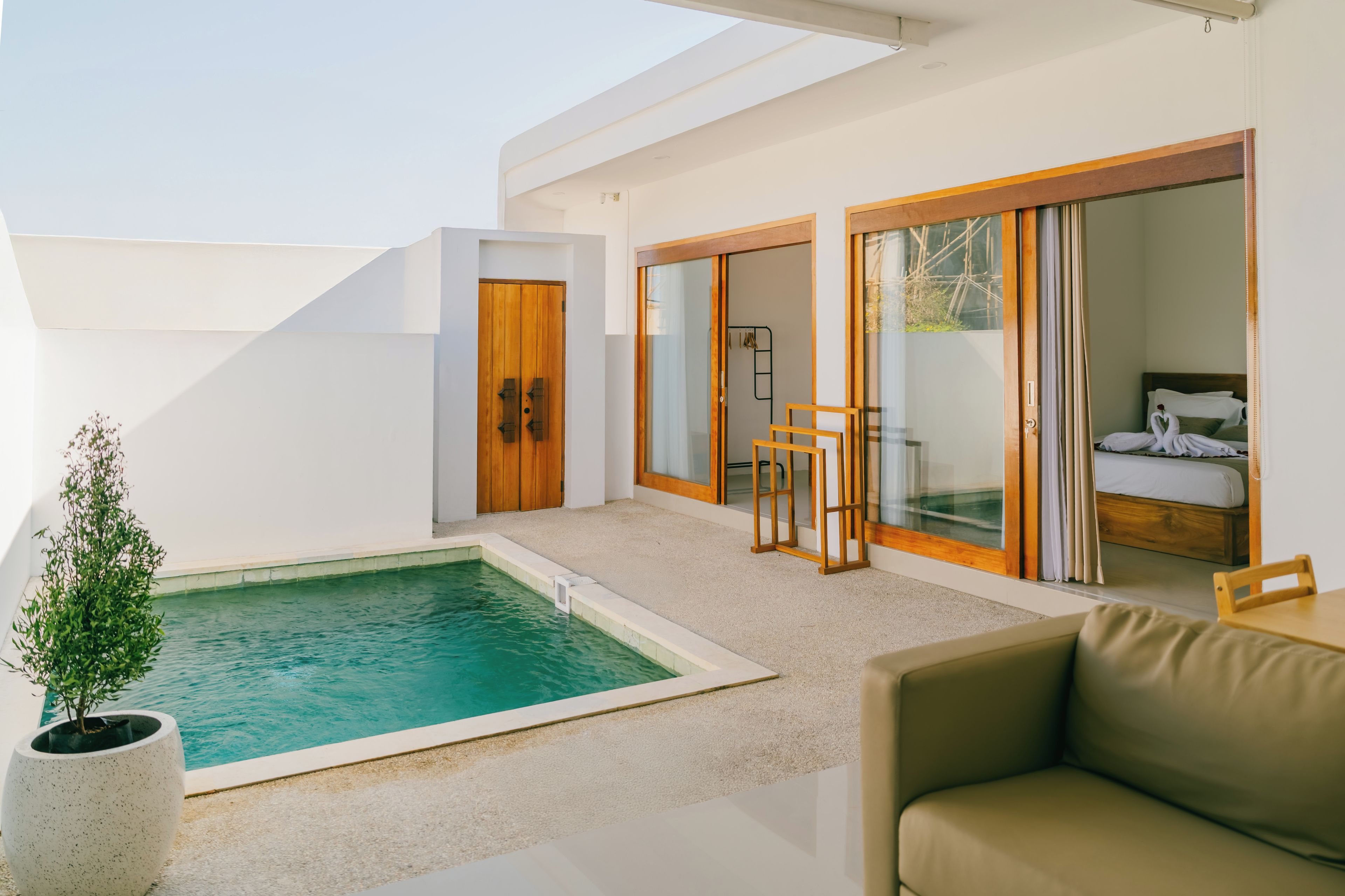 A modern outdoor pool area with a glass-enclosed bedroom and a seating area.