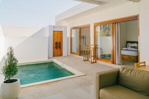 Un área de piscina moderna al aire libre con un dormitorio con paredes de vidrio y una zona de estar.