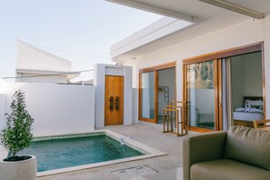 Área moderna de piscina externa, com porta de madeira, portas de correr de vidro e uma espreguiçadeira.