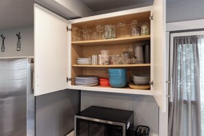 A kitchen with open cabinets containing glassware, plates, and bowls. - Kozy Cabin On the Lake (Stoughton)