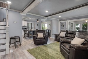 A spacious living area with leather sofas, a dining table, and a kitchen in the background. - Kozy Cabin On the Lake (Stoughton)