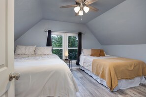 Ein Schlafzimmer mit zwei Betten, einem Deckenventilator und einem Fenster mit Vorhängen.