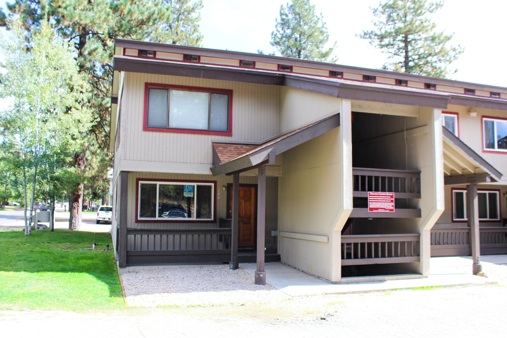 A two-story building with a covered front porch and a staircase leading to the second floor.
