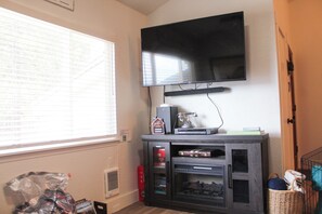 A room with a flat-screen TV mounted on the wall, a window with blinds, a fireplace, and a bookshelf. - 2 Baths, Fireplace, Coffee Bar, Pets Welcome (McCall)