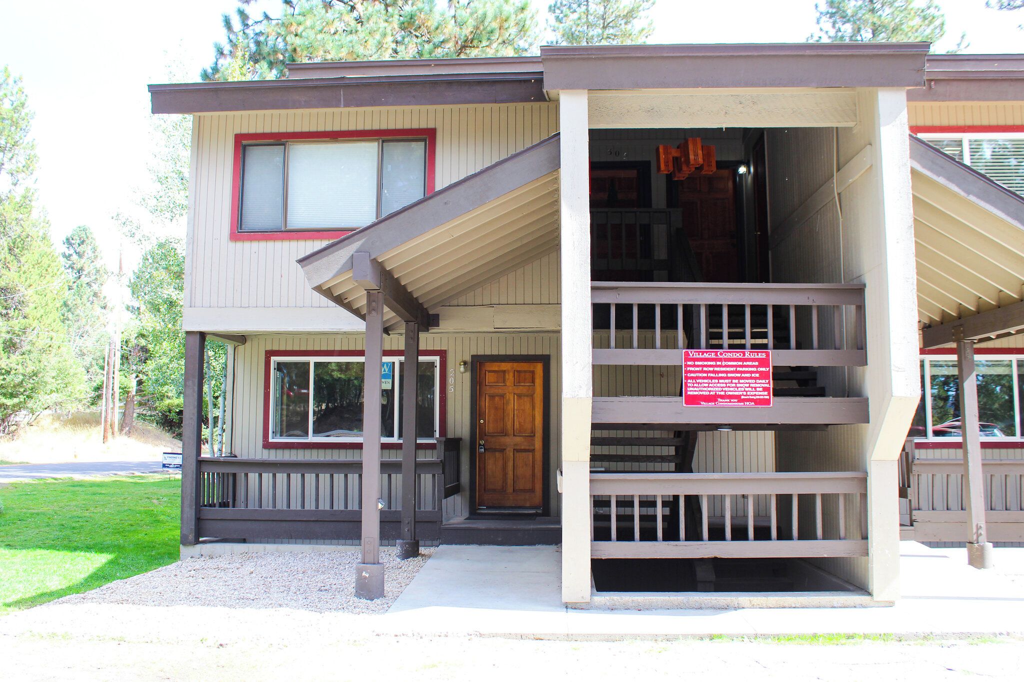 A two-story building with a porch and a sign indicating 'Village Condo Rules.'