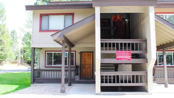 A two-story building with a porch and a sign indicating 'Village Condo Rules.'