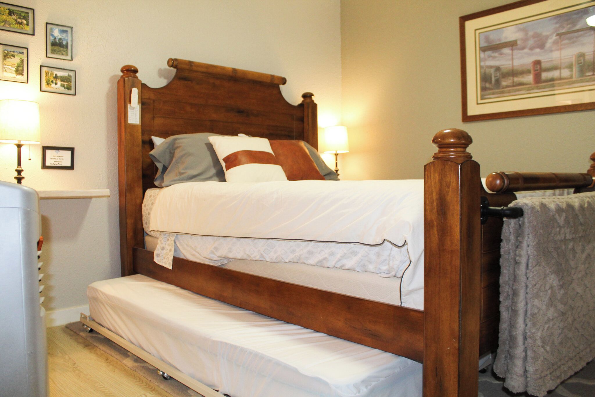 Een houten bed met hoofdeinde, nachtkastje en lamp.