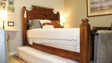 Een houten bed met hoofdeinde, nachtkastje en lamp.