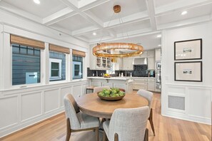 Cozinha moderna com armários brancos, uma mesa de jantar redonda e um lustre.