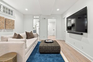 Ein modernes Wohnzimmer mit einer Couch, einem Couchtisch und einem an der Wand befestigten Fernseher.