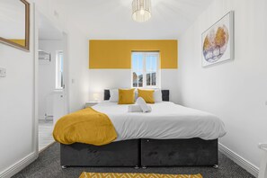 Een moderne slaapkamer met een bed, een raam en een schilderij aan de muur.