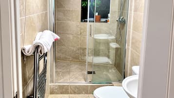 A bathroom with a glass-enclosed shower, a white toilet, and a sink.
