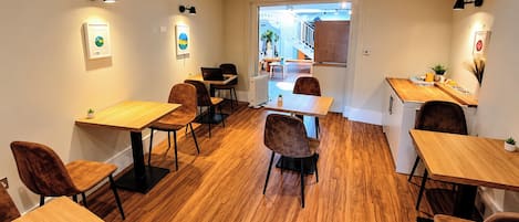 A modern interior with multiple wooden tables and chairs, a radiator, and wall-mounted lamps.