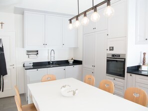 Eine moderne Küche mit weißen Schränken, einer schwarzen Arbeitsplatte und einem Esstisch mit Stühlen.