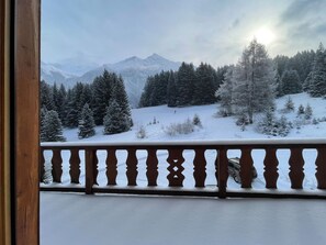 Eine verschneite Berglandschaft mit einem hölzernen Balkon.