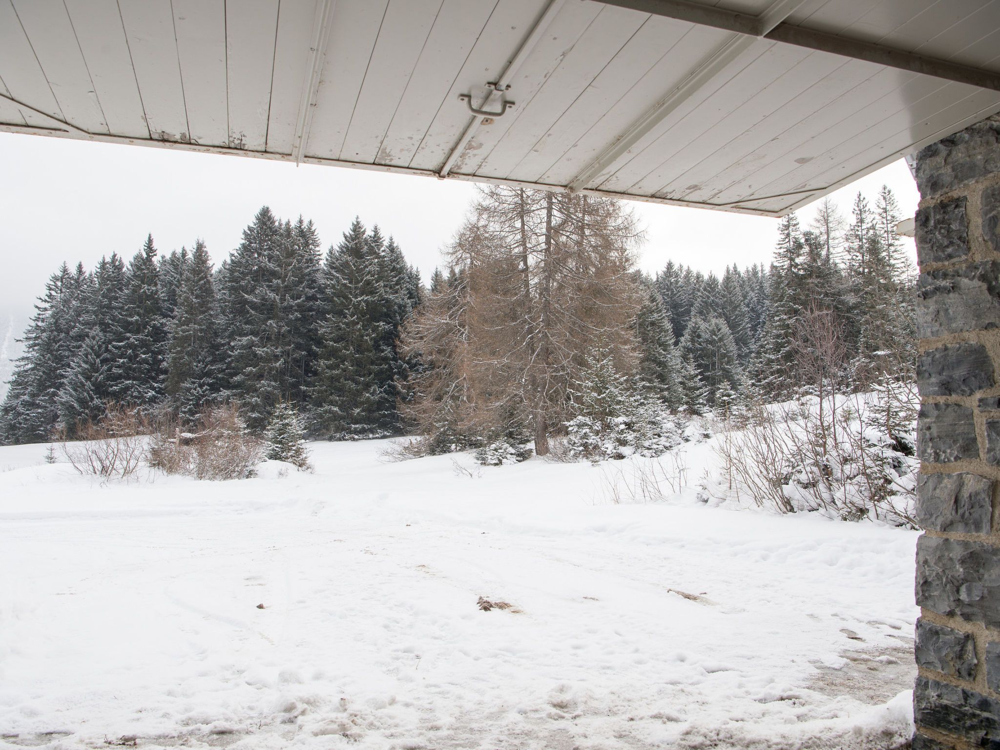 Schneebedeckte Landschaft mit einer Steinmauer und einem Holzdachaufbau.