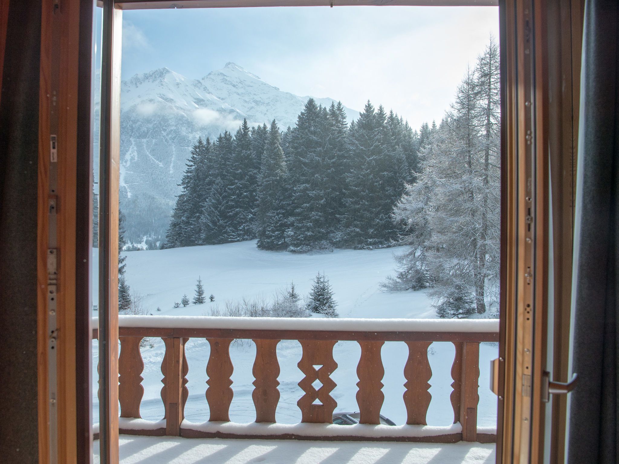 Un balcon offrant une vue sur un paysage enneigé, avec des arbres et des montagnes.