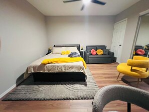 A bedroom with a bed, a grey sofa, a yellow armchair, and a grey armchair. - Charming Gold Suite - Entire Guest Unit-Tempe & ASU (Tempe)
