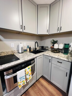 A kitchen with white cabinets, a black faucet, a coffee maker, and a dish rack. - Charming Gold Suite - Entire Guest Unit-Tempe & ASU (Tempe)
