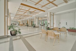 A spacious lobby with a high ceiling, large windows, and a central seating area with chairs. - Luxury 2BR Condo in Taguig | Free Parking & Balcony (Taguig)