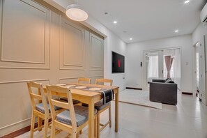 Un soggiorno moderno con zona pranzo, una TV a schermo piatto montata a parete e un divano grigio.