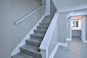 A staircase with a handrail and a landing area leading to a kitchen. - Your Chicago Home Between Homes - 4BR Furnished Home (Chicago)