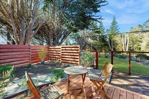 Eine Außenpatio mit einem Holztisch und -stühlen, umgeben von einem Holzzaun und einem Garten.