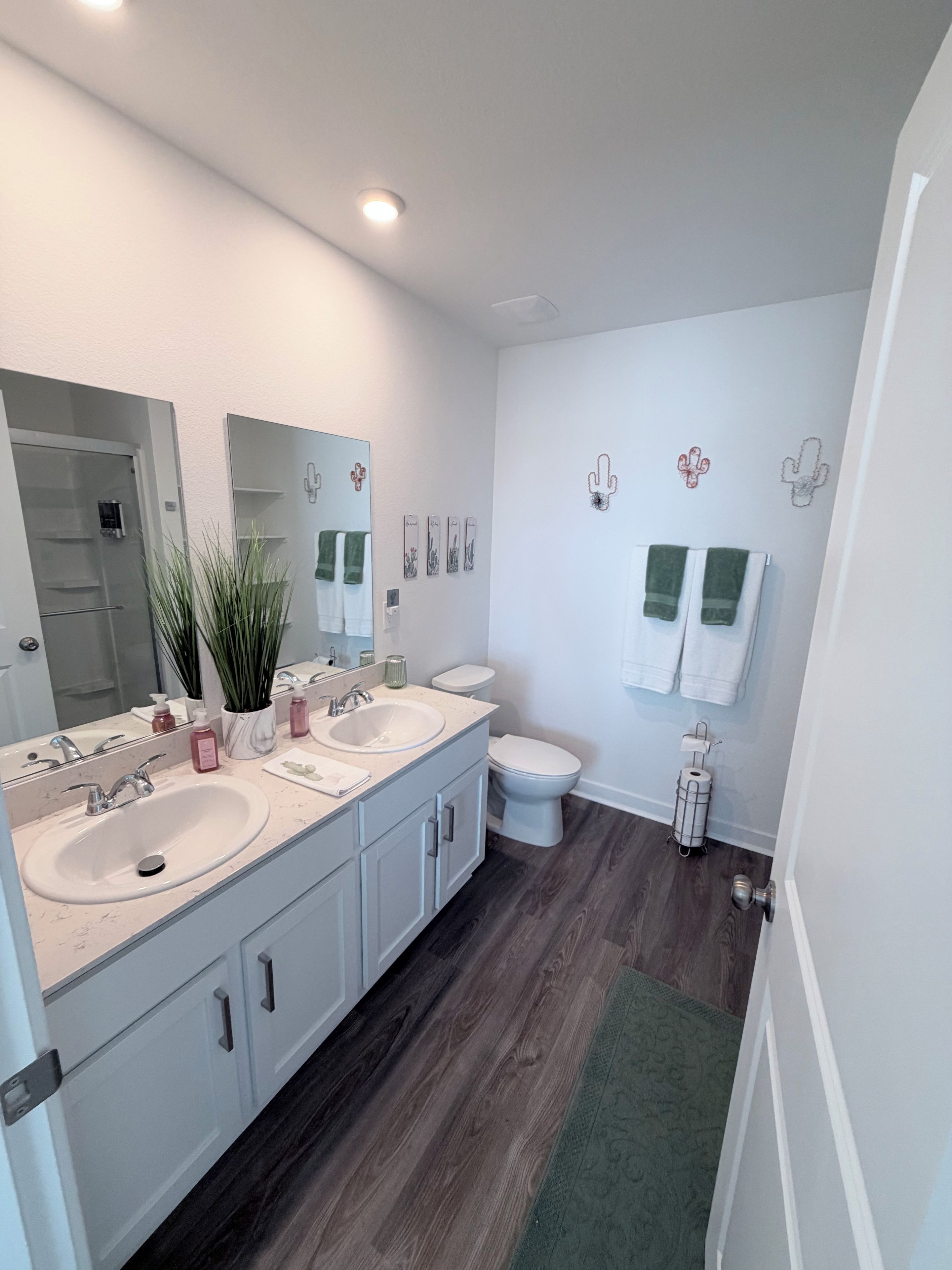 A modern bathroom with dual sinks, a large mirror, and a toilet.