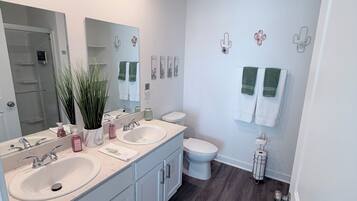 A modern bathroom with dual sinks, a large mirror, and a toilet.