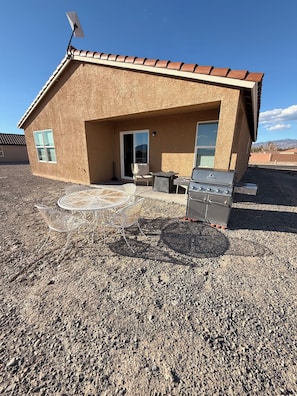 A single-story building with a patio area, a barbecue grill, and a satellite dish.