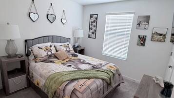 A bedroom with a bed, nightstands, a dresser, a window with blinds, and wall art.