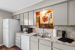 Una cocina moderna con refrigerador, microondas, lavamanos y un elegante salpicadero.