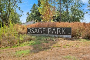Señal de Osage Park con el número 700, rodeada de vegetación y árboles naturales.