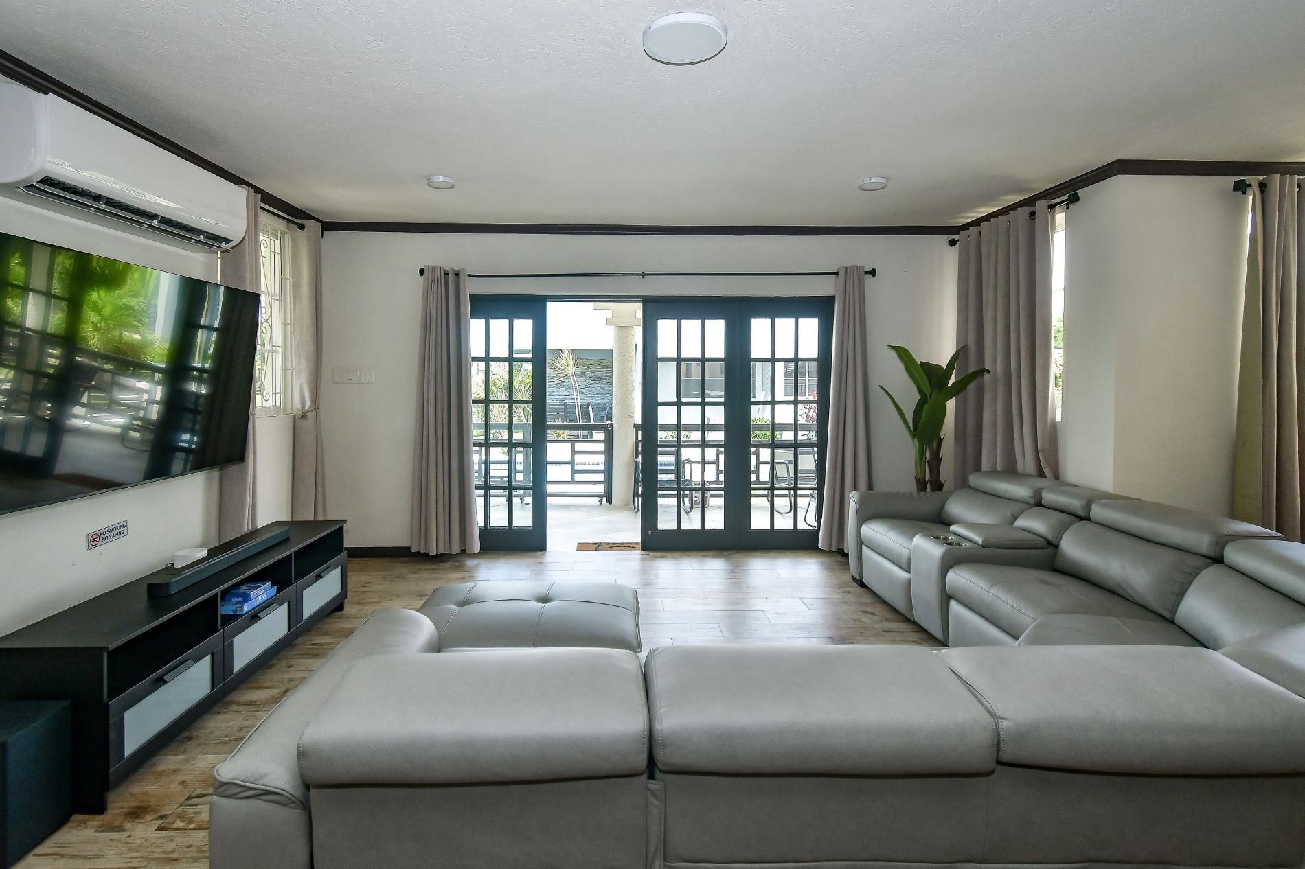 A modern living room with a sectional sofa, a flat-screen TV, and a sliding glass door leading to an outdoor area.