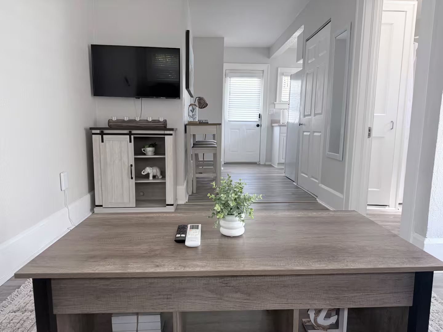 Une cuisine moderne avec une table en bois, un téléviseur fixé au mur et une plante sur la table.