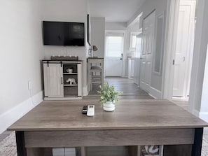 Eine moderne Küche mit einem Holztisch, einem an der Wand befestigten Fernseher und einer Pflanze auf dem Tisch.