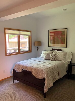 A bedroom with a bed, a window, a lamp, and a painting on the wall. - Cozy 2-bedroom house in a woodsy setting, near restaurants, shops, and more. (Pontiac)