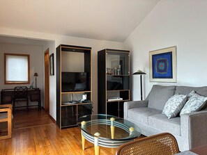 Ein modernes Wohnzimmer mit einem grauen Sofa, einem Glastisch und eingebauten Regale.