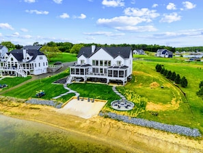 A large white house with a covered porch and multiple windows, surrounded by well-maintained lawns and a small pond. - Lakefront Lake Anna | Theater, Hot Tub, Beach (Mineral)