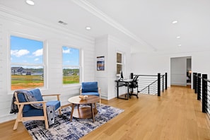 A spacious room with large windows, a wooden floor, a desk with a computer, and a blue chair. - Lakefront Lake Anna | Theater, Hot Tub, Beach (Mineral)