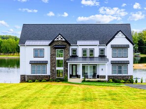 A two-story house with a stone facade, large windows, and a front porch. - Lakefront Lake Anna | Theater, Hot Tub, Beach (Mineral)
