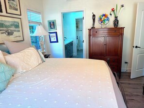 Ein Schlafzimmer mit Bett, Kommode und angrenzendem Badezimmer.