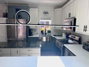 Una cocina moderna con electrodomésticos de acero inoxidable, armarios blancos y una encimera de mármol.